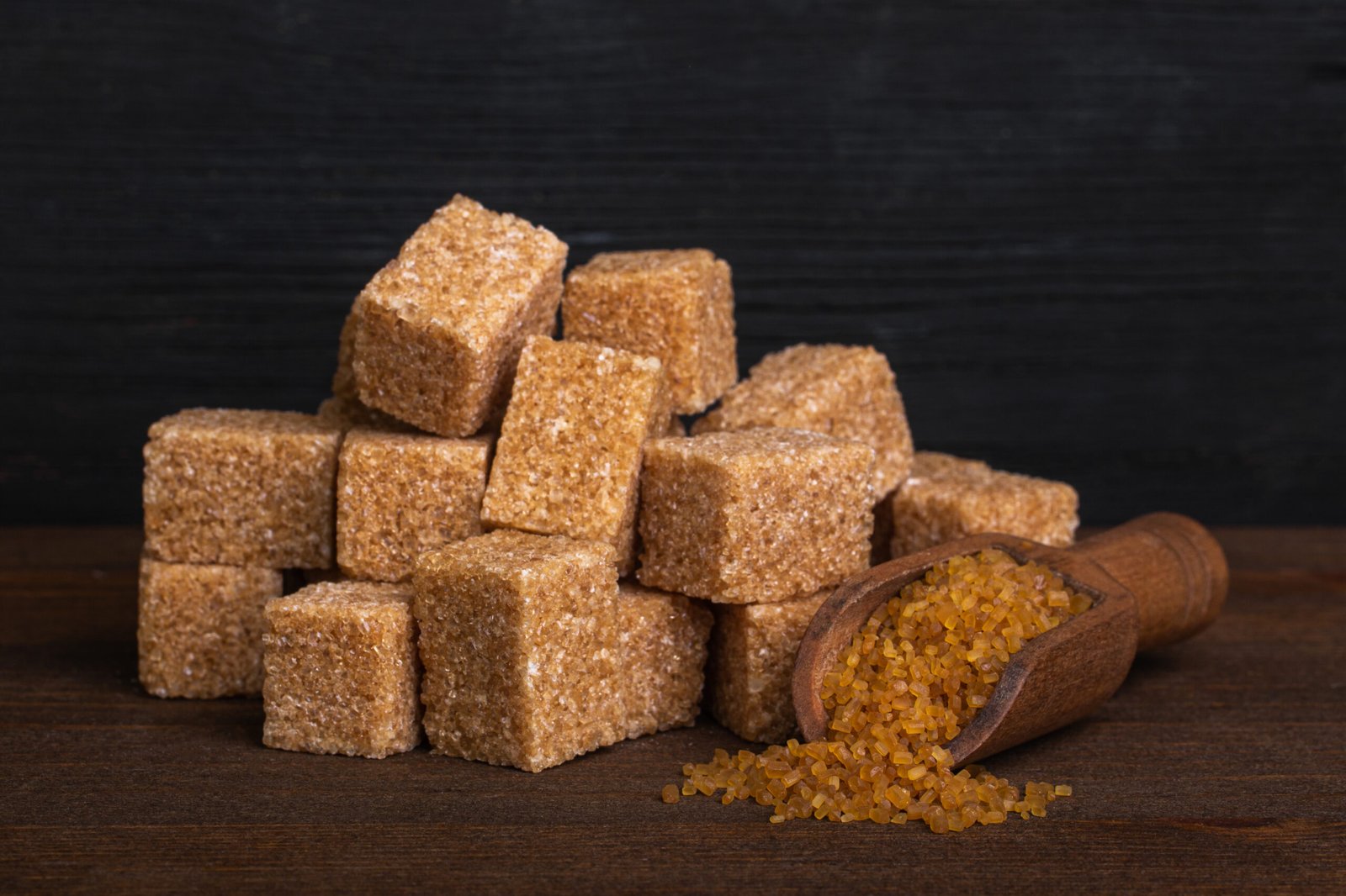 cubes of cane sugar and a wood spoon with sugar